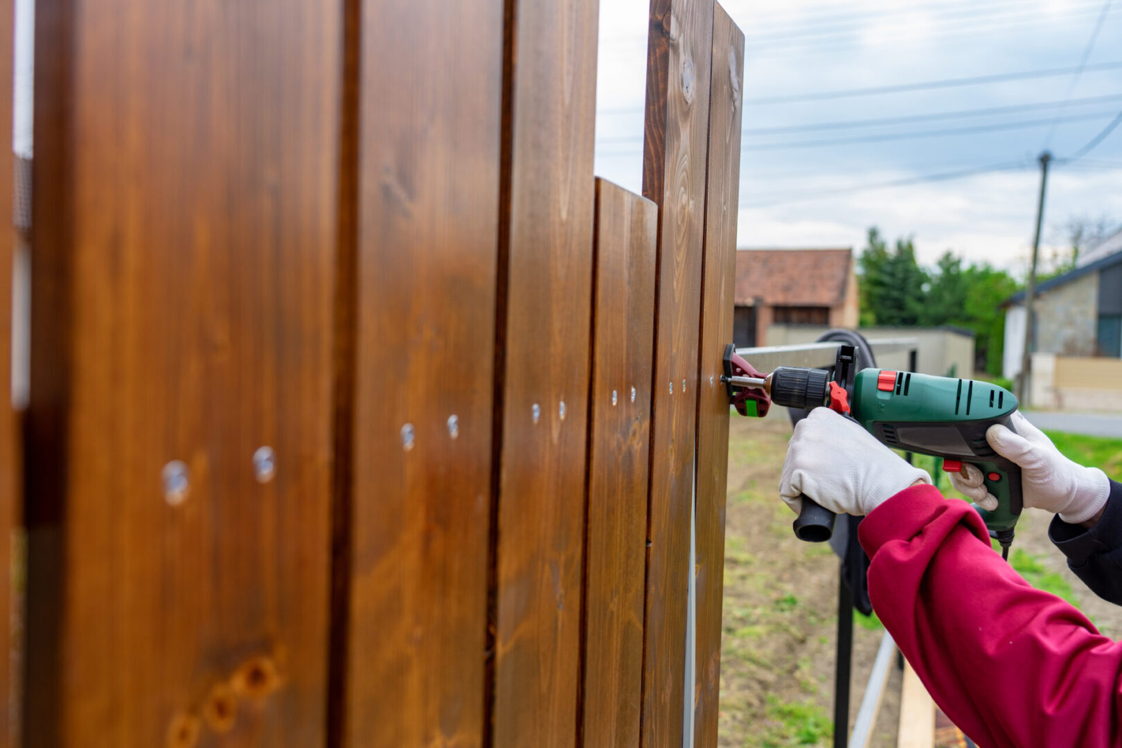 man building his own special wooden fence with driller ,